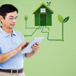Man with tablet and green house graphic against green background with eco-friendly home imagery